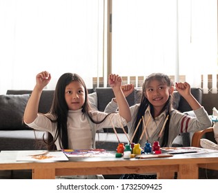 Two Little Girls Raise Hands Up In The Air With Happy Feeling,after Finish Painting Work.blurry Light Around