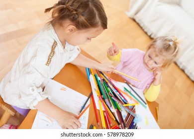 Two little girls sitting at home  and drawing. 