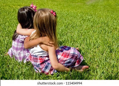 Two little girls sitting on grass