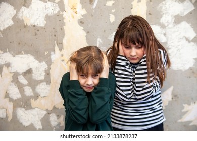 Two little girls   standing in   embrace at   destroyed wall and   afraid,   concept of   latest news in   world about Russia's attack on Ukraine - Shutterstock ID 2133878237