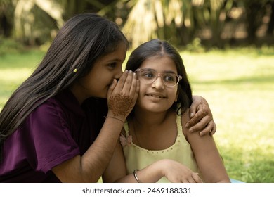 Two little girls whispering each other at park - Powered by Shutterstock