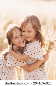 Two Little Happy Identical Twin Girls Playing Together In Nature In Summer. Girls Friendship And Youth Concept. Active Children's Lifestyle.