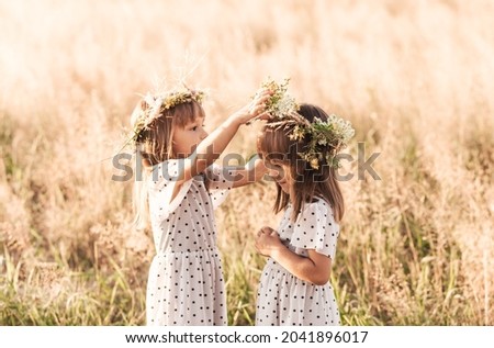 Two little happy identical twin girls playing together in nature in summer. Girls friendship and youth concept. Active children's lifestyle.