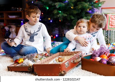 Two Little Kid Boys And Adorable Baby Girl Decorating Christmas Tree With Old Vintage Toys And Balls. Family Preaparation Celebration Of Family Feast. Children, Brothers And Sister In Festive Clothes