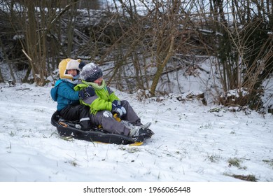 Two Little Kid Boys, Boy Brothers Playing Snow BOB Sled Having Fun In The Snowy Wintertime.