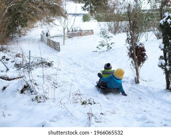 Two Little Kid Boys, Boy Brothers Playing Snow BOB Sled Having Fun In The Snowy Wintertime.