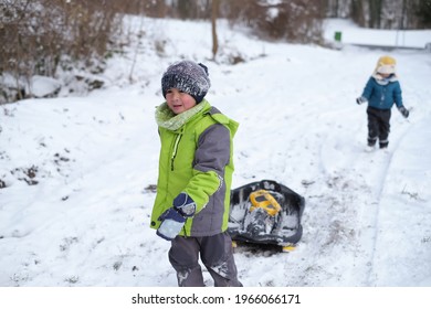 Two Little Kid Boys, Boy Brothers Playing Snow BOB Sled Having Fun In The Snowy Wintertime.