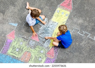 Two little kids boys drawing knight castle and colorful chalks asphalt  Happy siblings   friends having fun and creating chalk picture   painting  Creative leisure for children in summer 