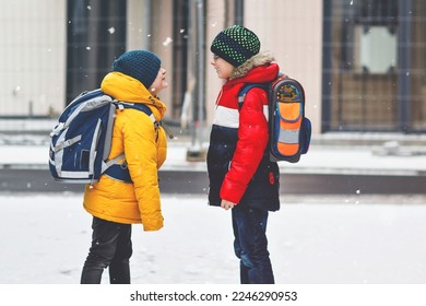 Two little kids boys of elementary class walking to school during snowfall. Happy children having fun and playing with first snow. Siblings and best friends with backpack in colorful winter clothes. - Shutterstock ID 2246290953