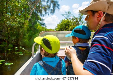 Two Little Kids Boys And Father Making Air Boat Tour In Florida Wetland Swamp At Everglades National Park In USA. Family, Dad And Children Discovering Wild Nature And Animals. Family Having Fun.