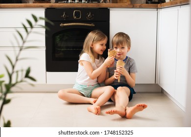 Two Little Kids Eating Ice Cream In Kitchen At Home, Smiling And Enjoying, Lifestyle 