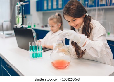 Two little kids in lab coat learning chemistry in school laboratory. Young scientists in protective glasses making experiment in lab or chemical cabinet. Working on a pc - Powered by Shutterstock