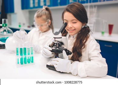 Two little kids in lab coat learning chemistry in school laboratory. Young scientists in protective glasses making experiment in lab or chemical cabinet. Looking through the microscope - Powered by Shutterstock