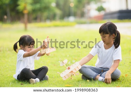 Two little kids playing with cardboard toy airplane in the park at the day time. Concept of happy game. Child having fun outdoors.