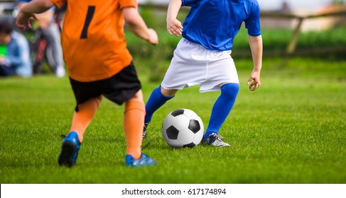 Two little kids playing football on grass field. Children kicking soccer training match. Young boys competing for ball. Two young boys in orange and blue shirts kicking soccer match on the field