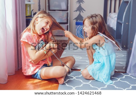 Two little mad angry girls sisters having fight at home. Friends girls can not share toy bag. Lifestyle authentic funny family moment of siblings quarrel. Kids bad behaviour. 