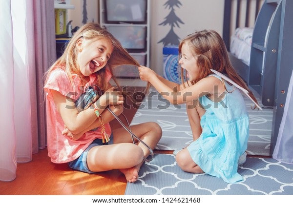 Two little mad\
angry girls sisters having fight at home. Friends girls can not\
share toy bag. Lifestyle authentic funny family moment of siblings\
quarrel. Kids bad behaviour.\
