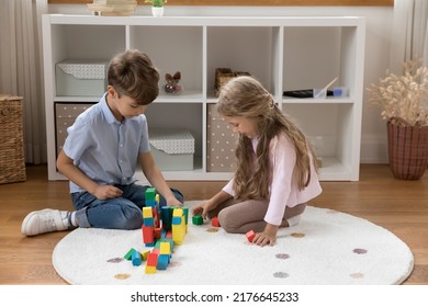 Two Little Sibling Kids Constructing House Model Together, Stacking Towers, Building Castle From Toy Blocks. Brother And Sister Playing Alone On Heating Warm Floor In Home Playroom