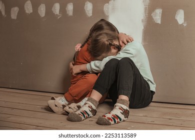 two little sister girls hugged and crying in the attic of the house, they are scared. domestic violence and a dysfunctional family with underage children - Shutterstock ID 2253113589
