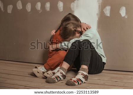 two little sister girls hugged and crying in the attic of the house, they are scared. domestic violence and a dysfunctional family with underage children