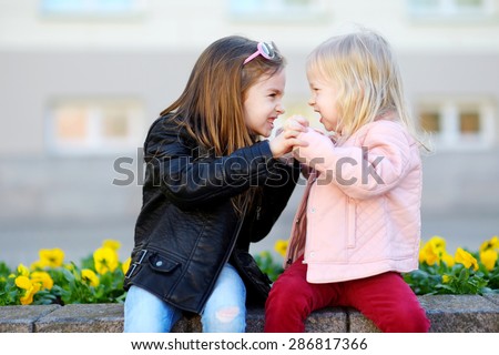 Two little sisters fighting outdoors