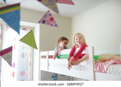 Two little sisters fooling around, playing and having fun in twin bunk bed on sunny sunday morning