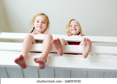 Two little sisters fooling around, playing and having fun in twin bunk bed on sunny sunday morning