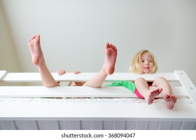 Two little sisters fooling around, playing and having fun in twin bunk bed on sunny sunday morning