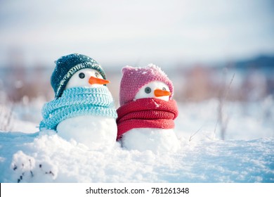 Two little snowmen the girl and the boy in knitted caps and scarfs on snow in the winter. Festive background with a lovely snowman. Christmas card, copy space - Powered by Shutterstock