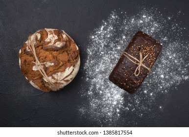 Two loafs of bread on black background with flour