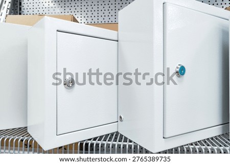 Two lockable storage boxes are positioned next to each other on a shelf. They are white and designed to keep items secure.