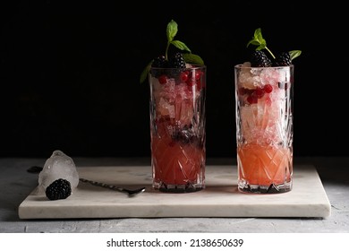 Two Long Glasses With Non-alcoholic Mocktail Version Of The Classic Blackberry And Gin Cocktail Bramble On Marble Board