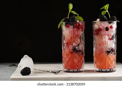 Two Long Glasses With Non-alcoholic Mocktail Version Of The Classic Blackberry And Gin Cocktail Bramble On Marble Board