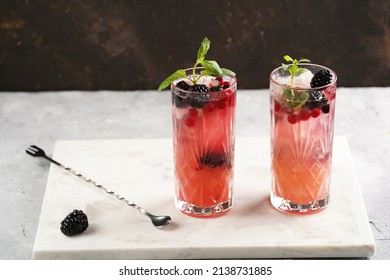 Two Long Glasses With Non-alcoholic Mocktail Version Of The Classic Blackberry And Gin Cocktail Bramble On Marble Board