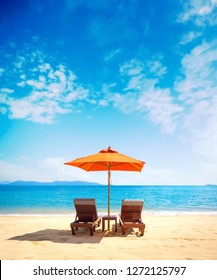 Two Lounge Chairs With Sun Umbrella On A Beach