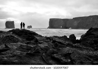 Two love birds look off into the distance of the Icelandic landscape, the cliffs where thunderous crashing waves are heard and the seas the show signs of humble life by way of a playful seal. - Shutterstock ID 1020597007