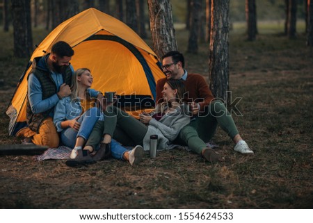 Two lovely couples sitting in front of their tent while camping