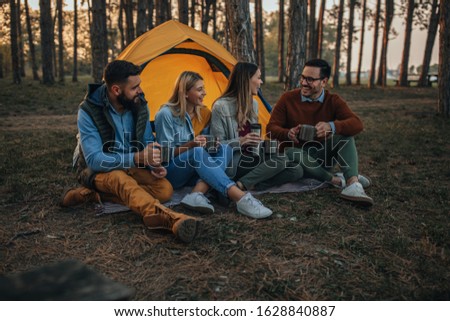 Two lovely couples sitting in front of their tent while camping