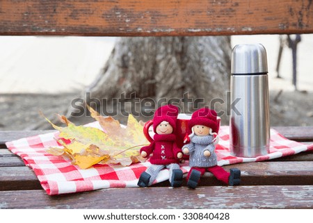 Two lovely dolls at bench with thermos