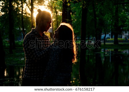 Two lovers in the back light. Silhouetted photo in the park. Love, relationship concept