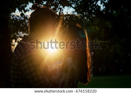 Two lovers in the back light. Silhouetted photo in the park. Love, relationship concept