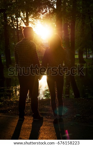 Two lovers in the back light. Silhouetted photo in the park. Love, relationship concept