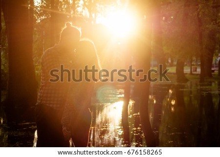 Two lovers in the back light. Silhouetted photo in the park. Love, relationship concept