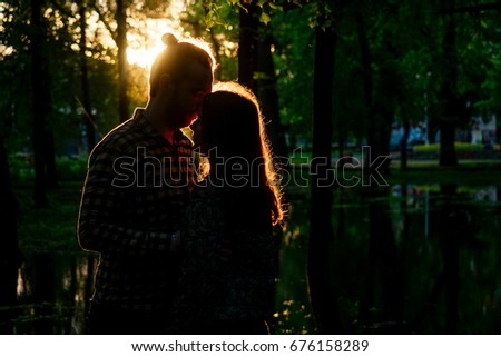 Two lovers in the back light. Silhouetted photo in the park. Love, relationship concept
