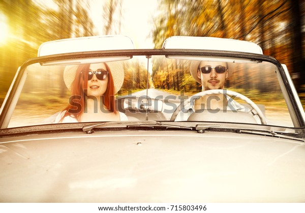 two
lovers in cabriolet and autumn road of orange leaves
