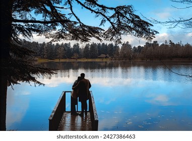 Two lovers are hugging each other against the view on the pier.