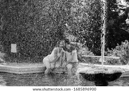 Two lovers kissing each other with their feets in the fountain