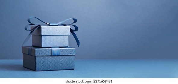 Two Luxury gift boxes with a blue bow on dark blue. Side view monochrome . Fathers day or Valentines day gift for him. Corporate gift concept or birthday party. Festive sale copy space banner - Shutterstock ID 2271659481