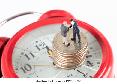 Two Macro Small People Talking About Business On Coins And Coins On Broken Alarm Clock