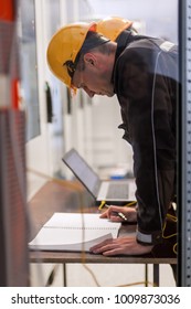 Two maintenance engineers inspect relay protection system with laptop computer. Bay control unit. Medium voltage switchgear - Shutterstock ID 1009873036